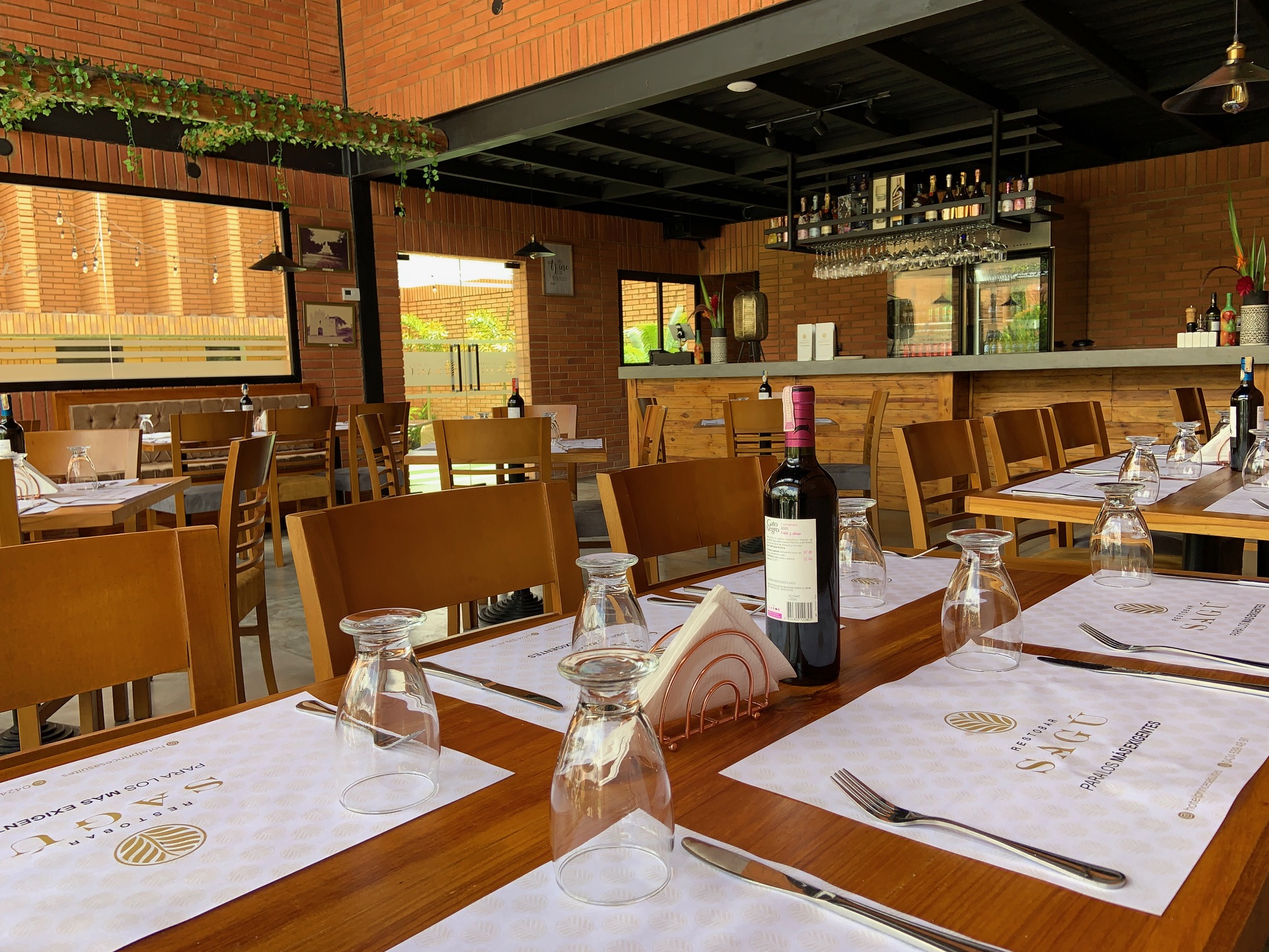 Interior elegante de un restaurante con mesas de madera preparadas para los comensales.